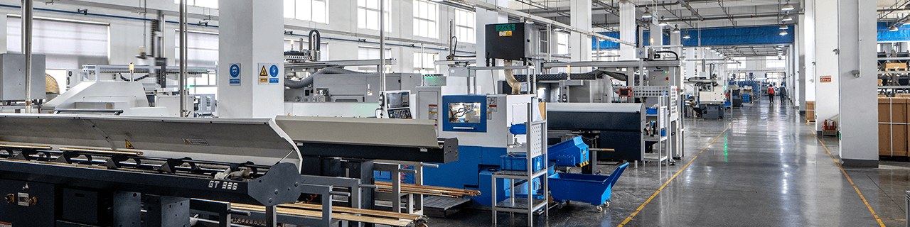 Interior factory view of a long walkway with a row of CNC machines highlighting the scale of the facility.